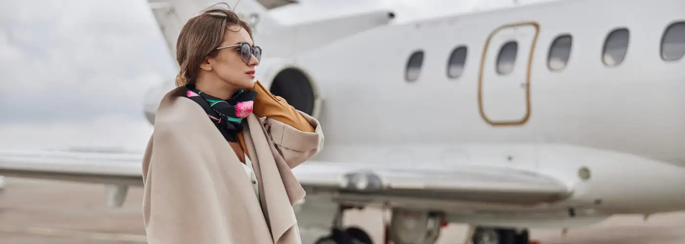 Well-dressed woman standing next to a jet plane