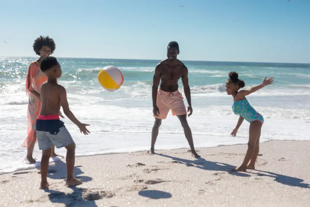 Family playing with beach ball by the ocean