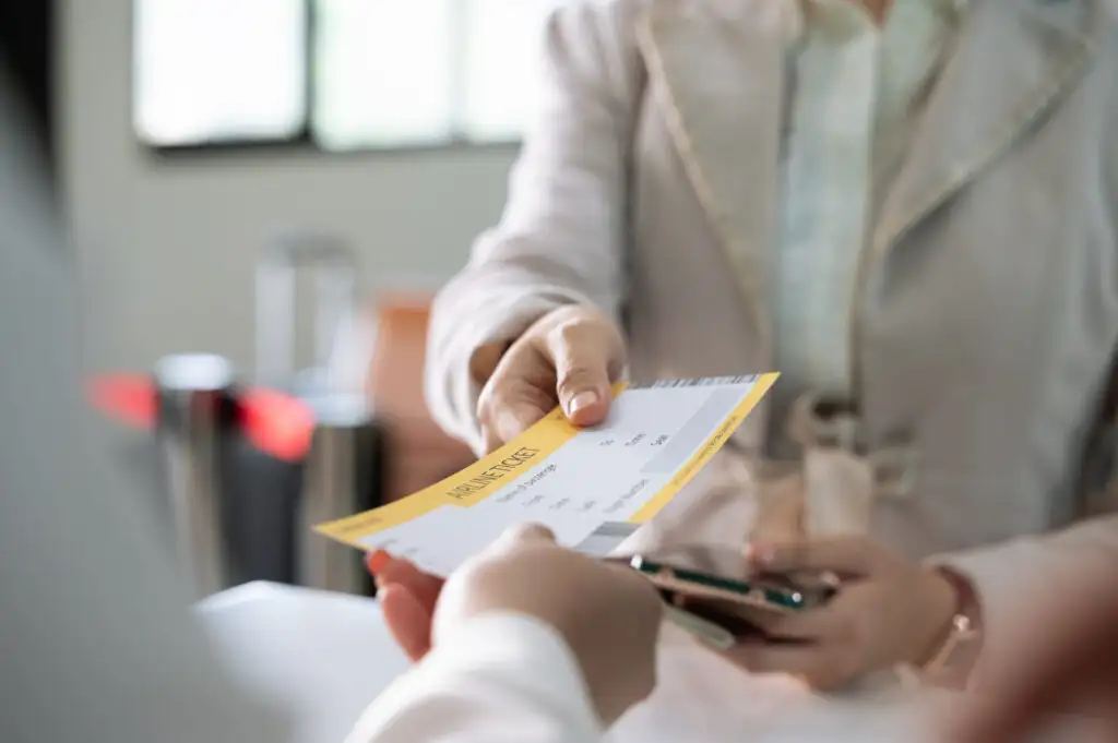 Close up of woman being handed an airline ticket by gate agent