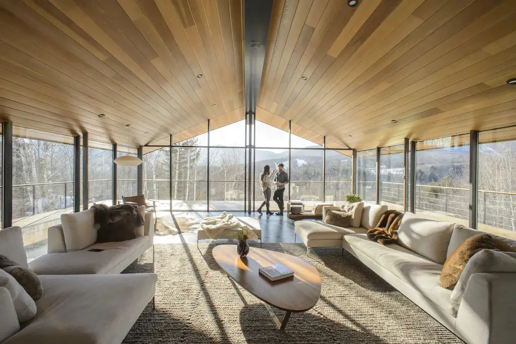 Two people chatting in a large living area with entirely glass walls