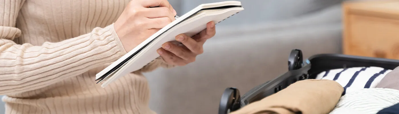 Woman packing suitcase using checklist