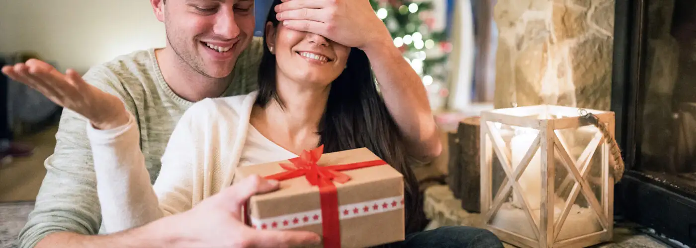 couple opening christmas gift fireplace