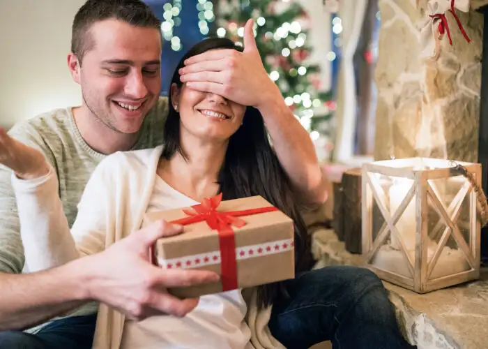 couple opening christmas gift fireplace