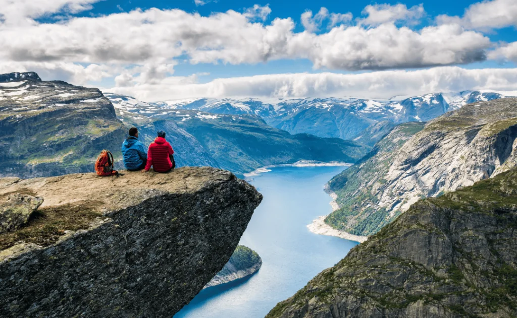 Couple sitting against amazing nature view on the way to Trolltunga. Location - Scandinavian Mountains, Norway, Stavanger