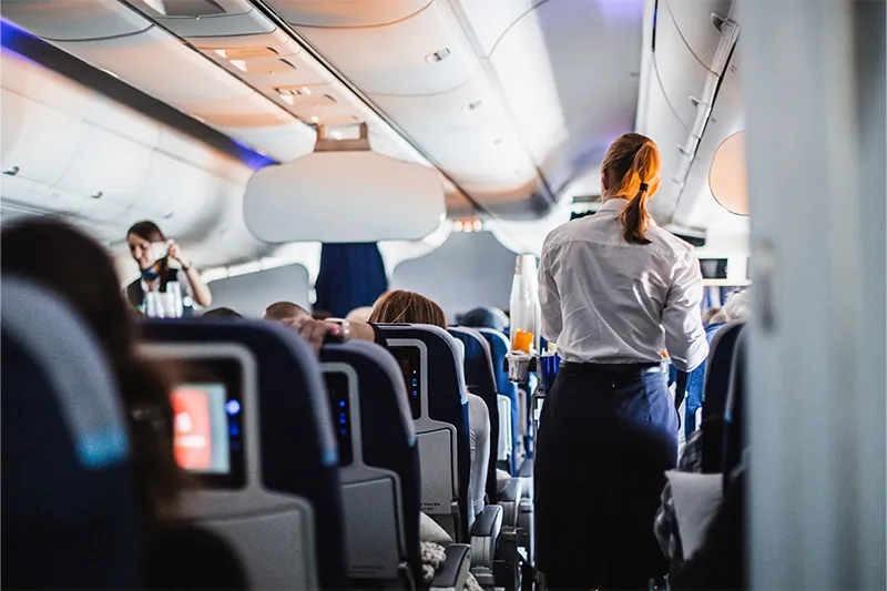 Flight attendant moving through aisles with cart