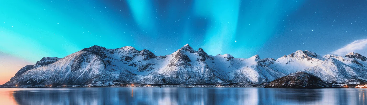 Northern lights and snow covered mountains in Lofoten islands, Norway. Aurora borealis. Starry sky with polar lights and snowy rocks reflected in water.