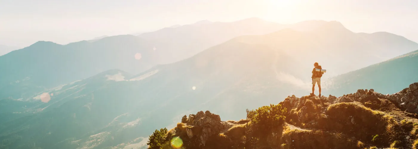 Mountain hiker with backpack tiny figurine stay on mountain peak with beautiful panorama