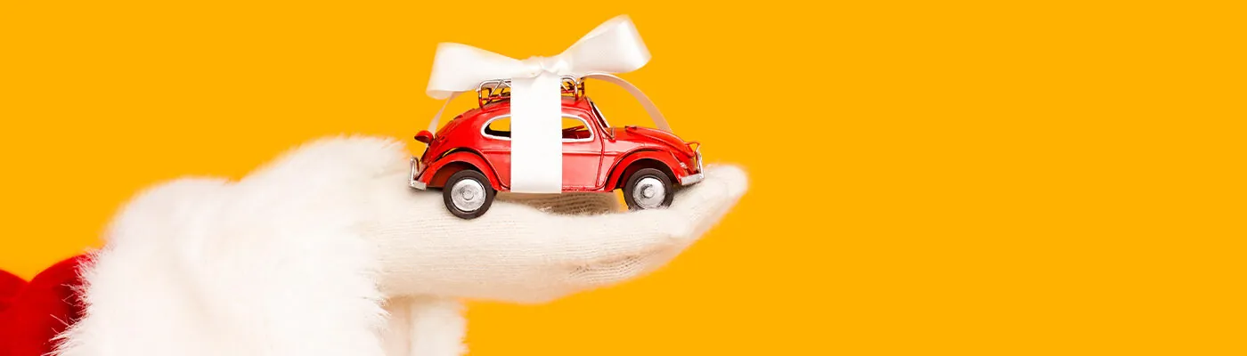 Santa's hand holding a small red toy car with ribbon around it