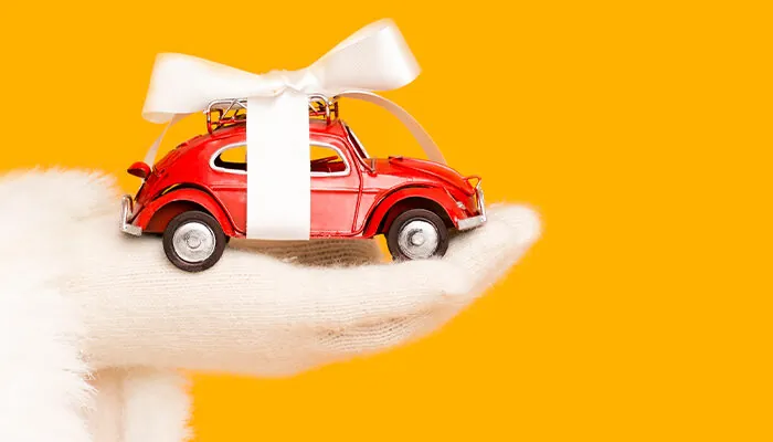 Santa's hand holding a small red toy car with ribbon around it