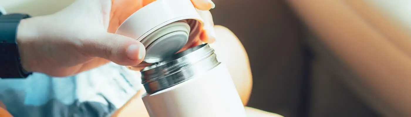 Close up of person's hands holding an insulated water bottle in a car