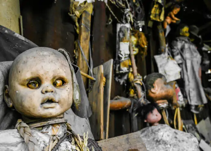 Several dolls in various states of decay displayed along a wall