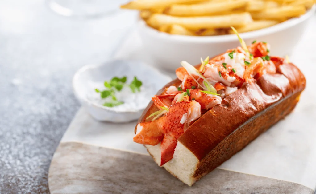 Lobster roll on a brioshe bun with fries on a marble board