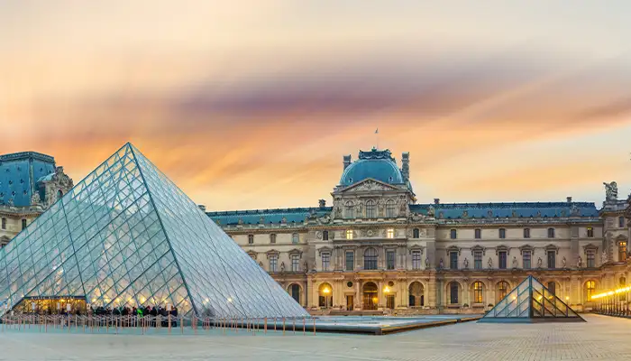 View of famous Louvre Museum with Louvre Pyramid at evening at sunset in Paris France