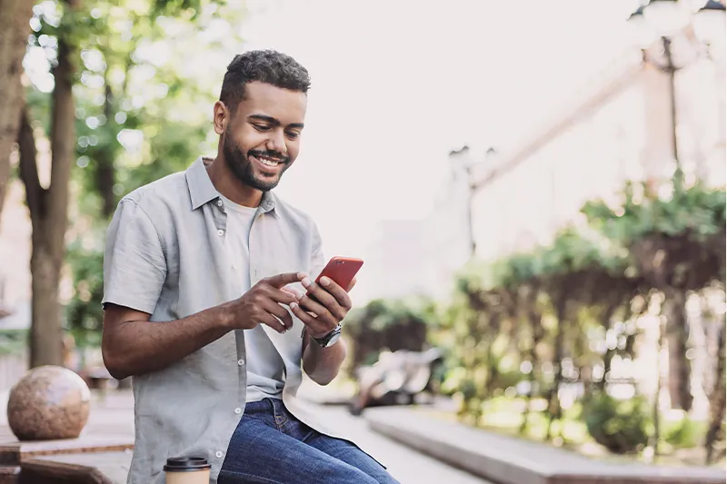 Man using phone while sitting outside on a sunny day