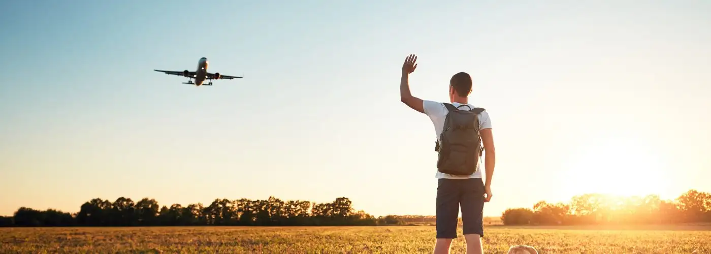 man waving at airplane overhead.