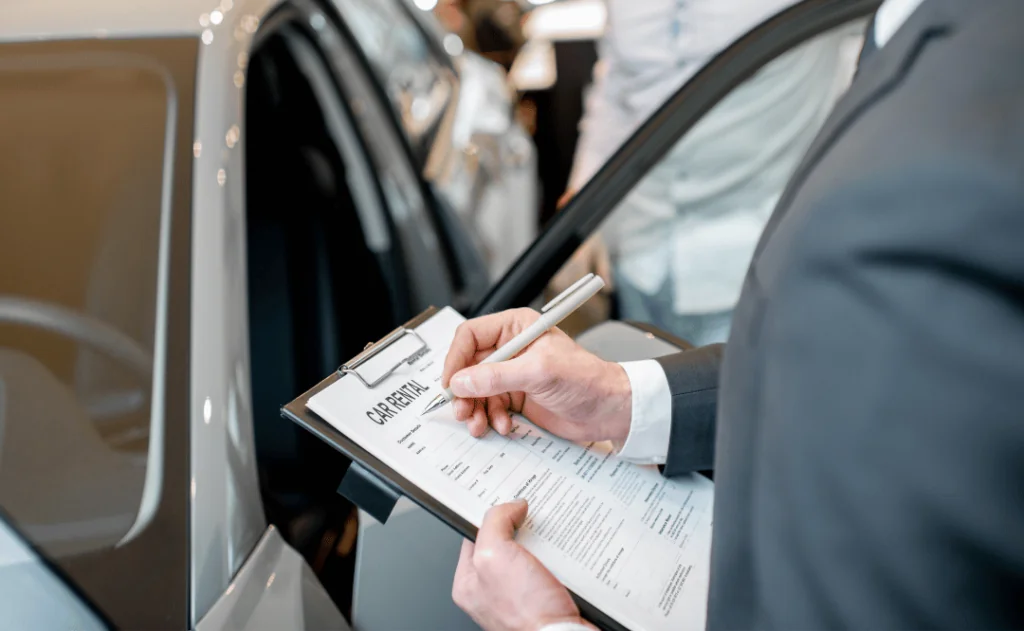 Manager filling car rental documents standing in the showroom with car on the background