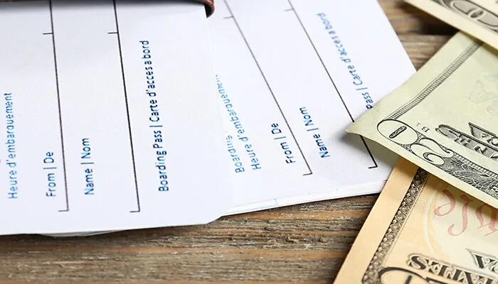 Airline tickets and cash on wooden table