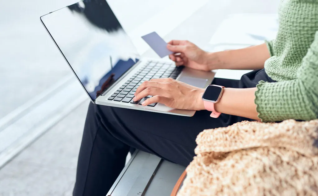 Young Asian girls holding credit card and using laptop computer shopping online while checking flight or online check-in at airport