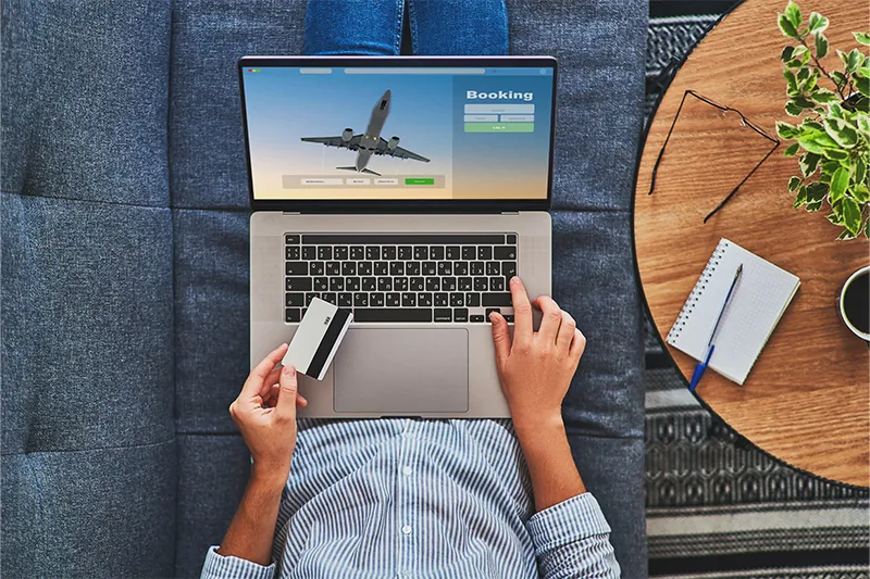 Overhead view of someone booking flights on their laptop