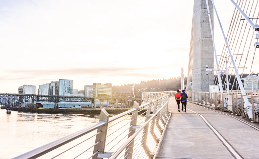 A couple walks over the Tilikum Crossing Bridge near sunset in Portland, Oregon.