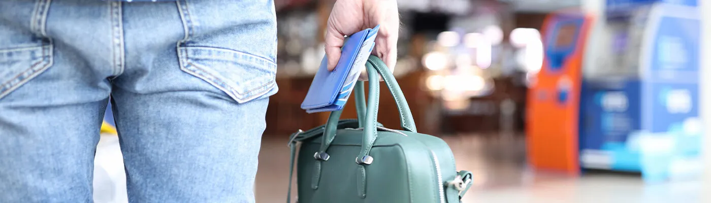 Man holds bag with a passport and tickets in his hand while standing at airport