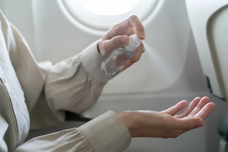 Close up of person using hand sanitizer on plane