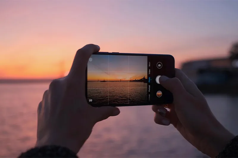 Close up of person taking a sunset photo with their smartphone