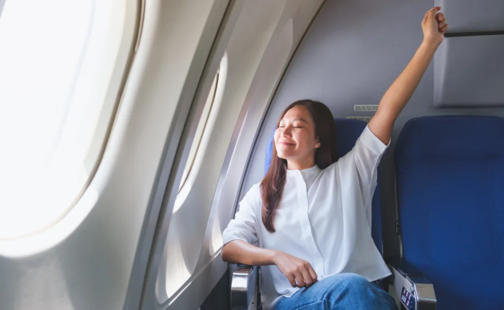 Portrait image of a woman stretching on an airplane