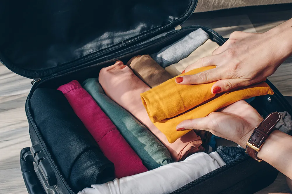 Woman rolling clothes and packing them