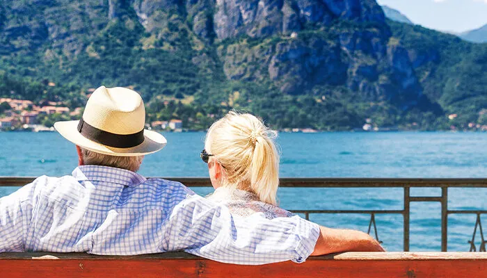 Senior couple sitting on bench enjoying a waterfront view in Italy