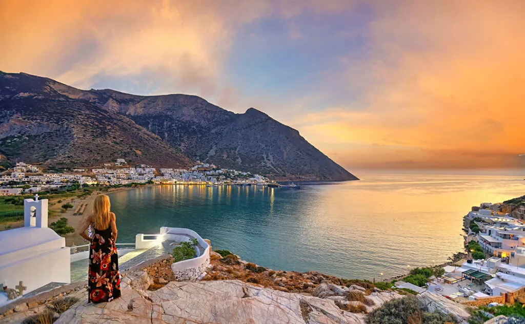 A woman looking from Agia Marina at Kamares beach of Sifnos island at sunset, Greece