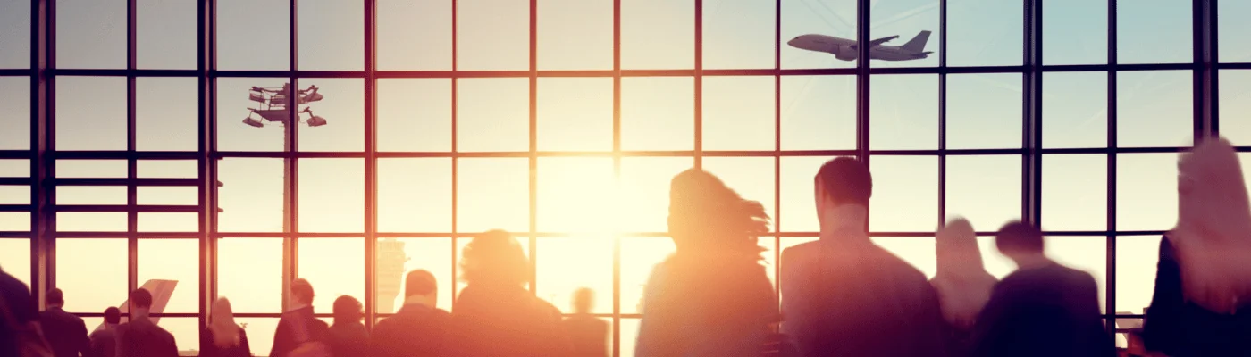 Silhouettes of people in a crowded airport at sunset