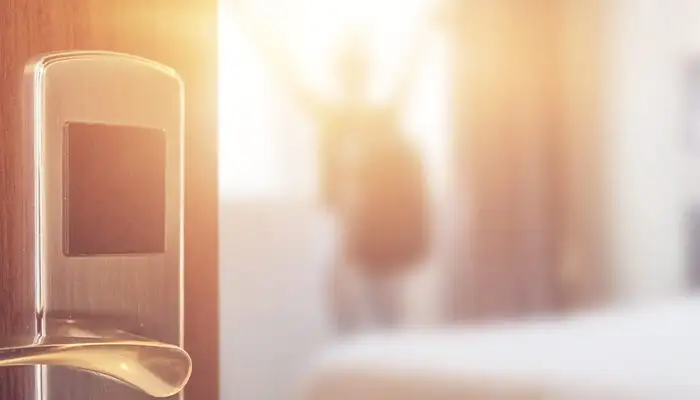 Blurry image of a person opening the curtains of a hotel room as seen from the doorway