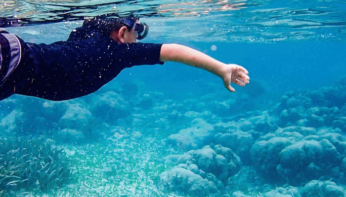 Underwater image of boy snorkeling through coral reef near Ambergris Caye, Belize