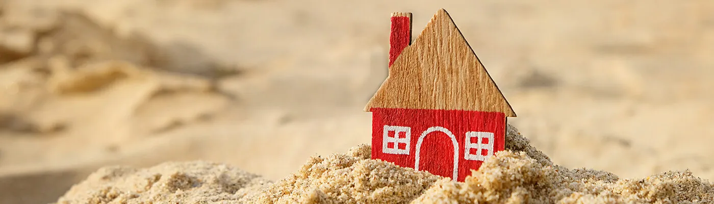 Small wooden model of a house in the sand