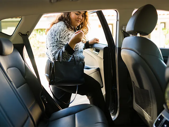 Woman getting into the backseat of a rideshare