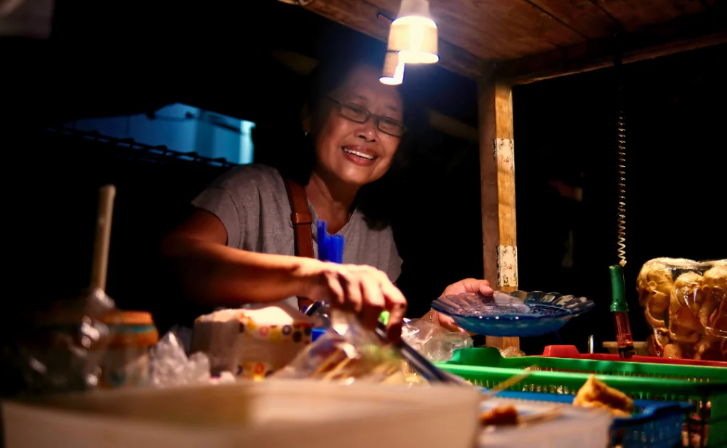 Woman selling Angkringan street food on the road side of Yogyakarta