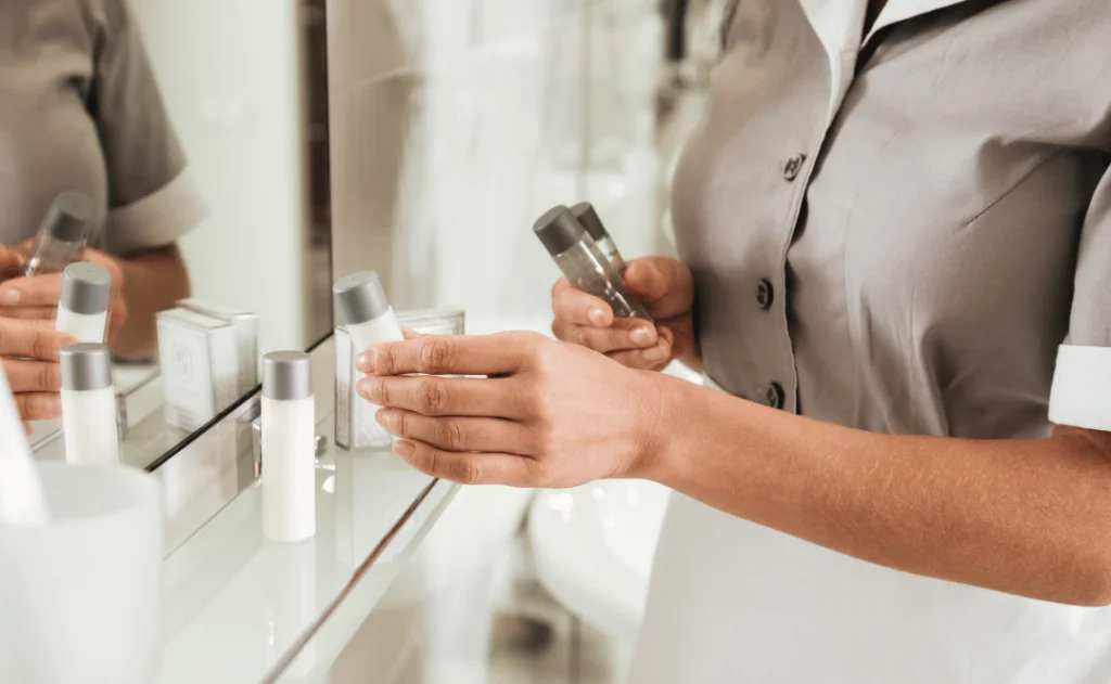 Young hotel maid putting bath accessories in a bathroom