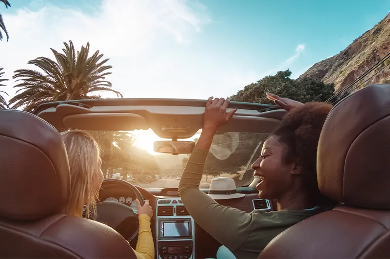 Two young women driving a convertible on a sunny day